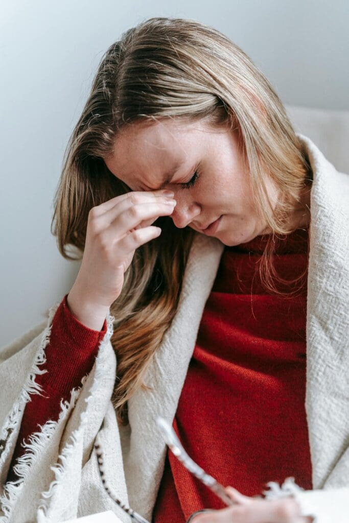 Woman pressing the top of her nose due to migraine pain seeking chiropractic care
